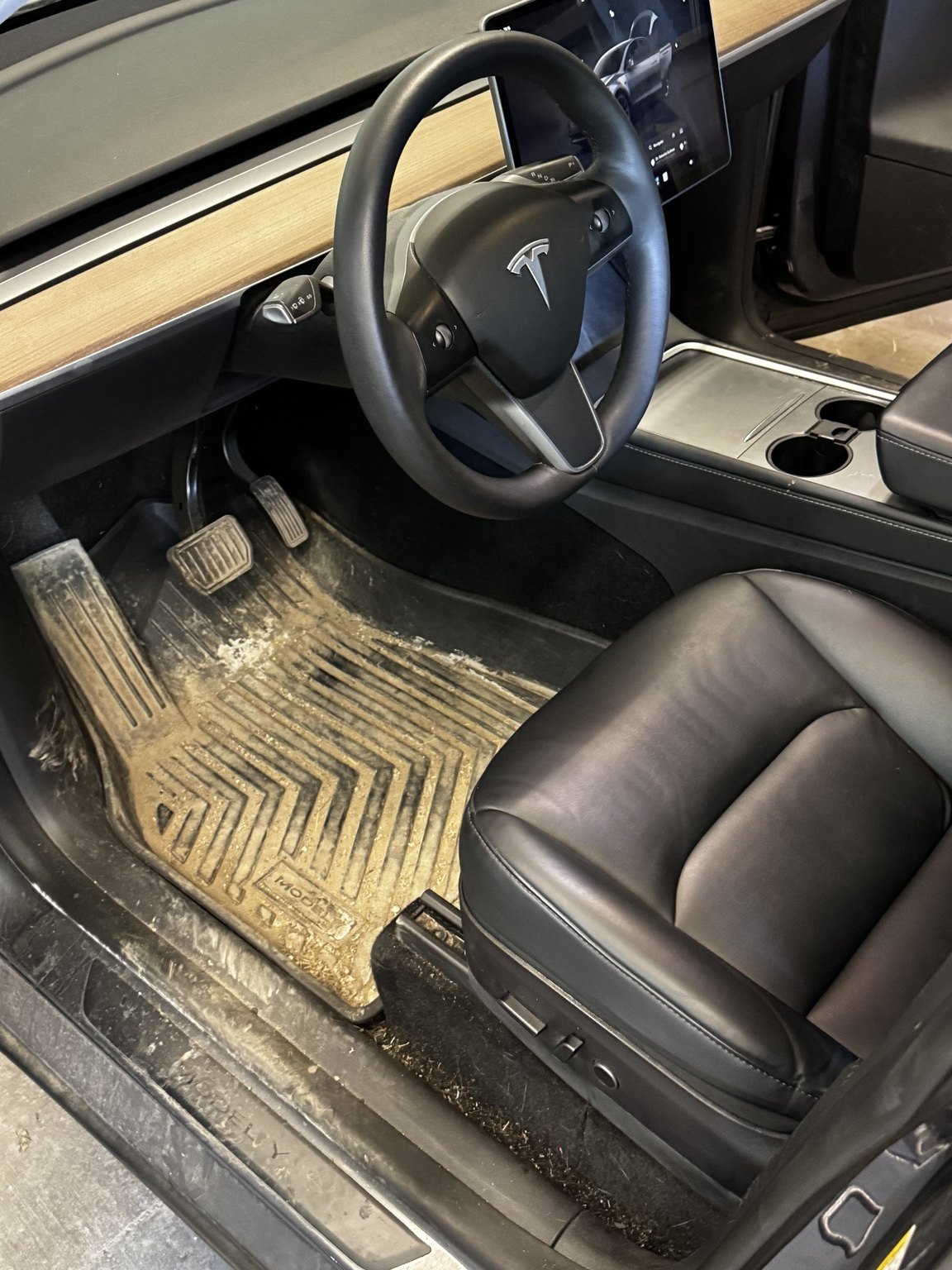 Before photo of a dirty Tesla front floor mat and front cabin